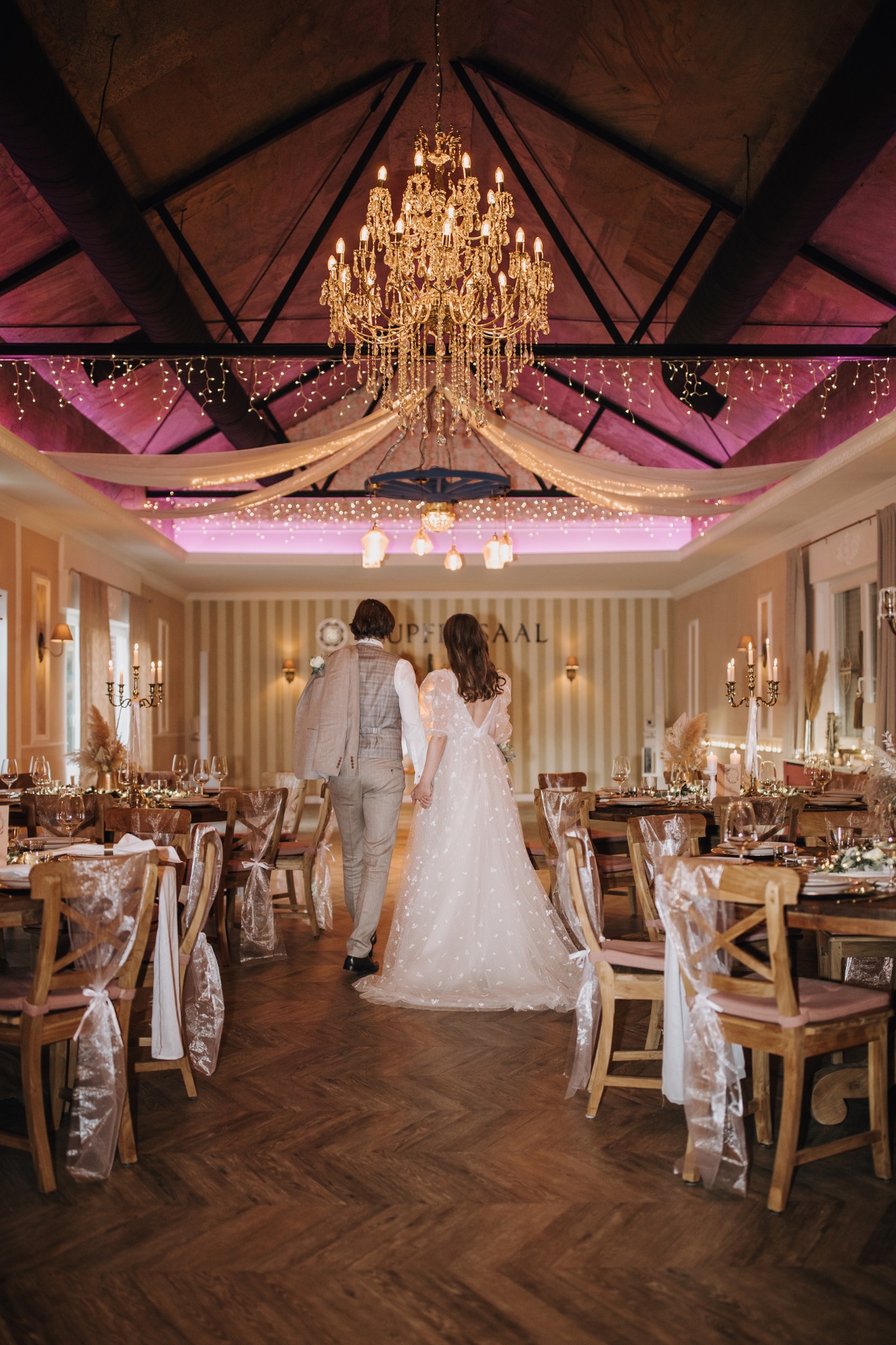 Beleuchteter Kupfersaal mit Kronleuchter und Hochzeitspaar
